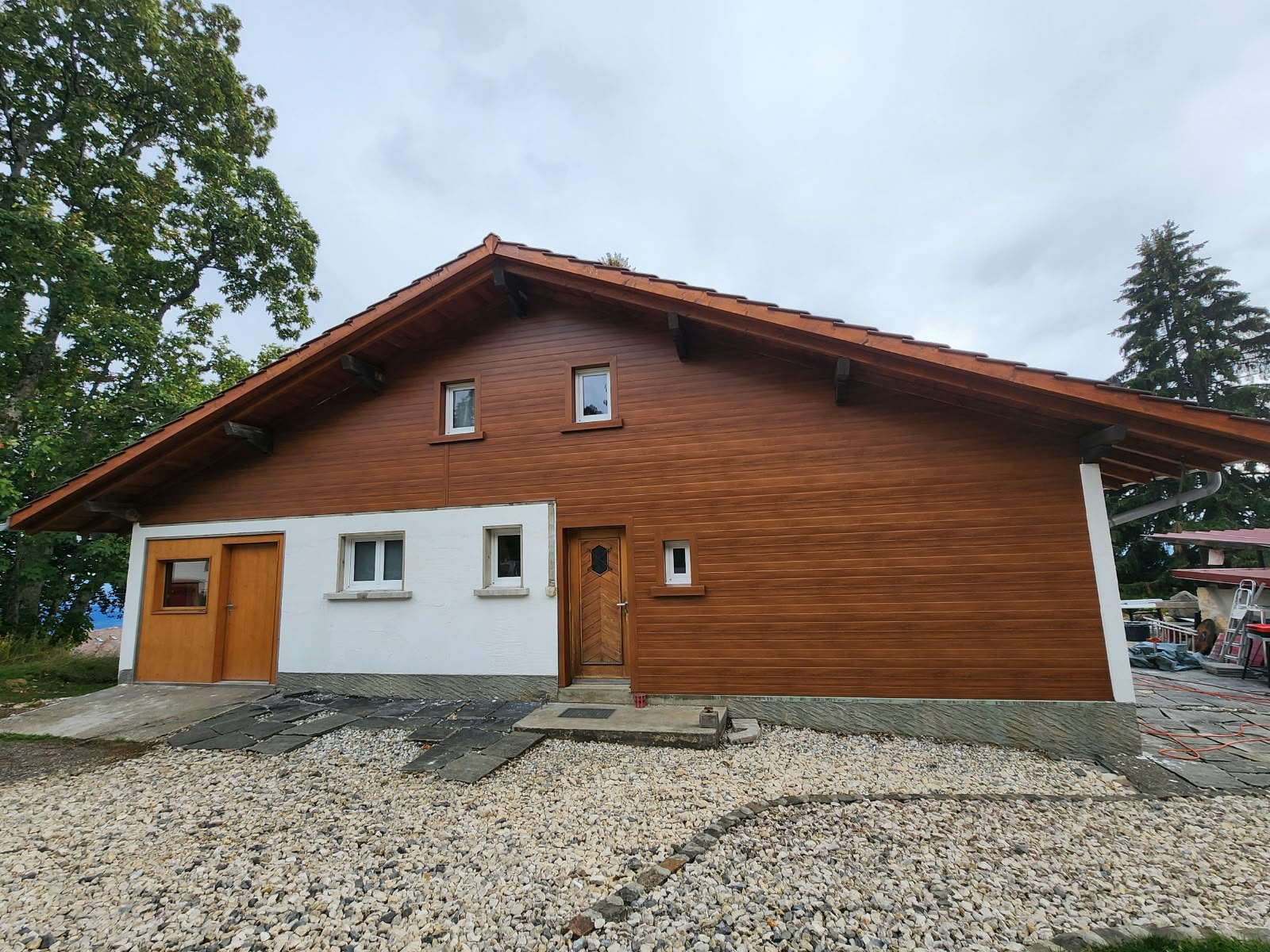 Maison individuelle en Suisse terminée : façade avant isolée par l’extérieur, clin lisse Chêne Doré pose horizontale